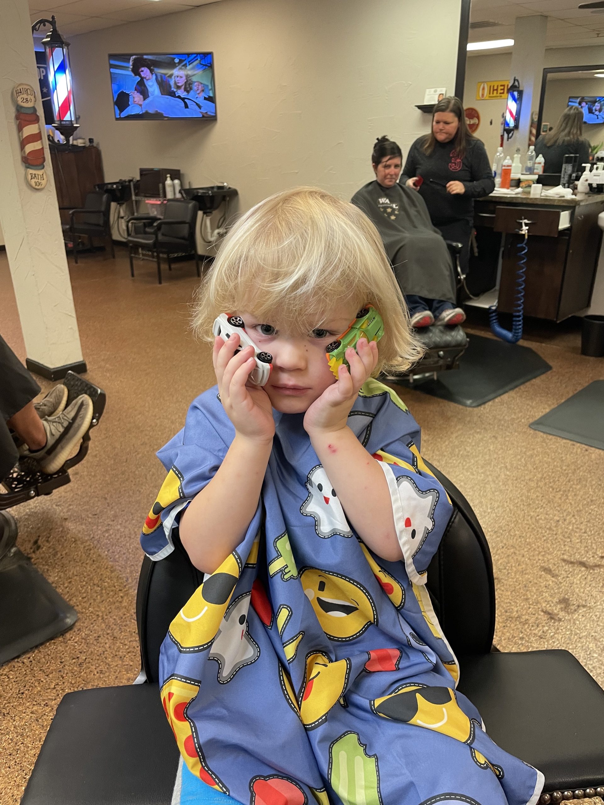 child holding toy cars before haircut